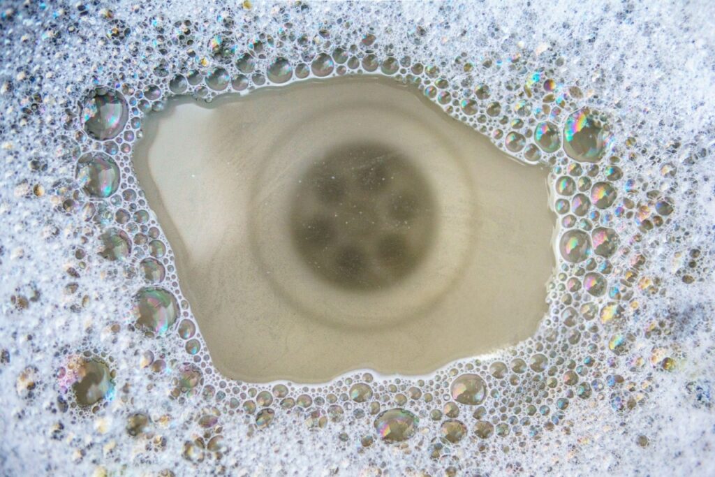 Drain cleaning in Mapleton with soapy water swirling into a household drain by Summit Plumbing Pros.