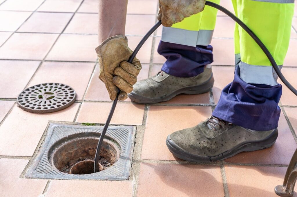 Drain cleaning in Murray with a technician using a drain snake to clear a floor drain.