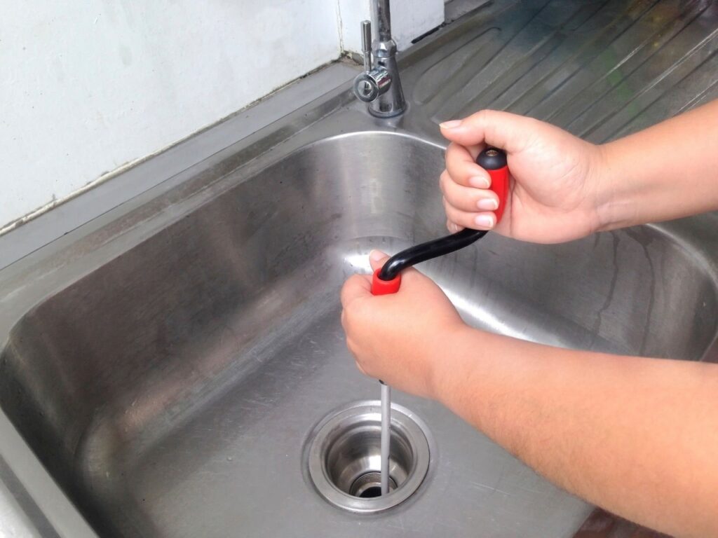 Drain cleaning in Taylorsville with a hand auger clearing a kitchen sink drain by Summit Plumbing Pros.