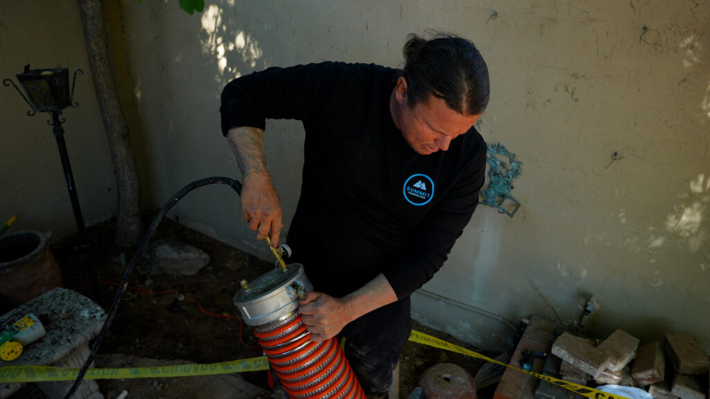 Drain cleaning in Millcreek by Summit Plumbing Pros technician using professional drain cleaning equipment outdoors.